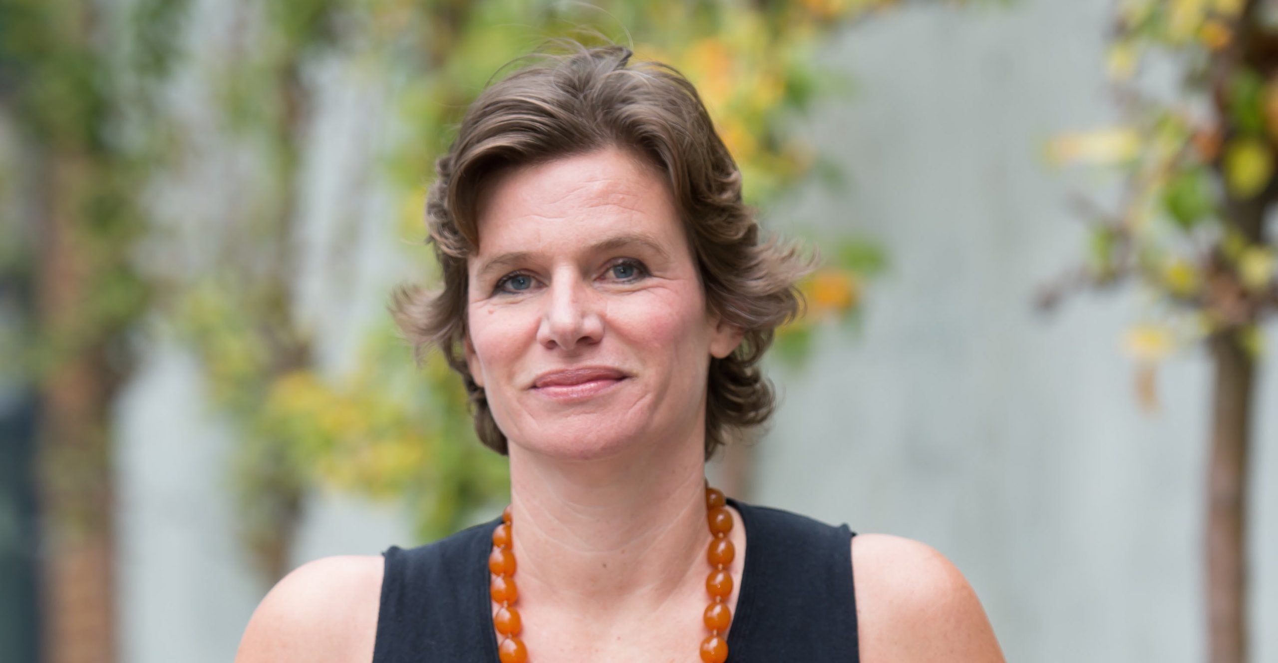 Professor Mariana Mazzucato wearing a black shirt and orange necklace