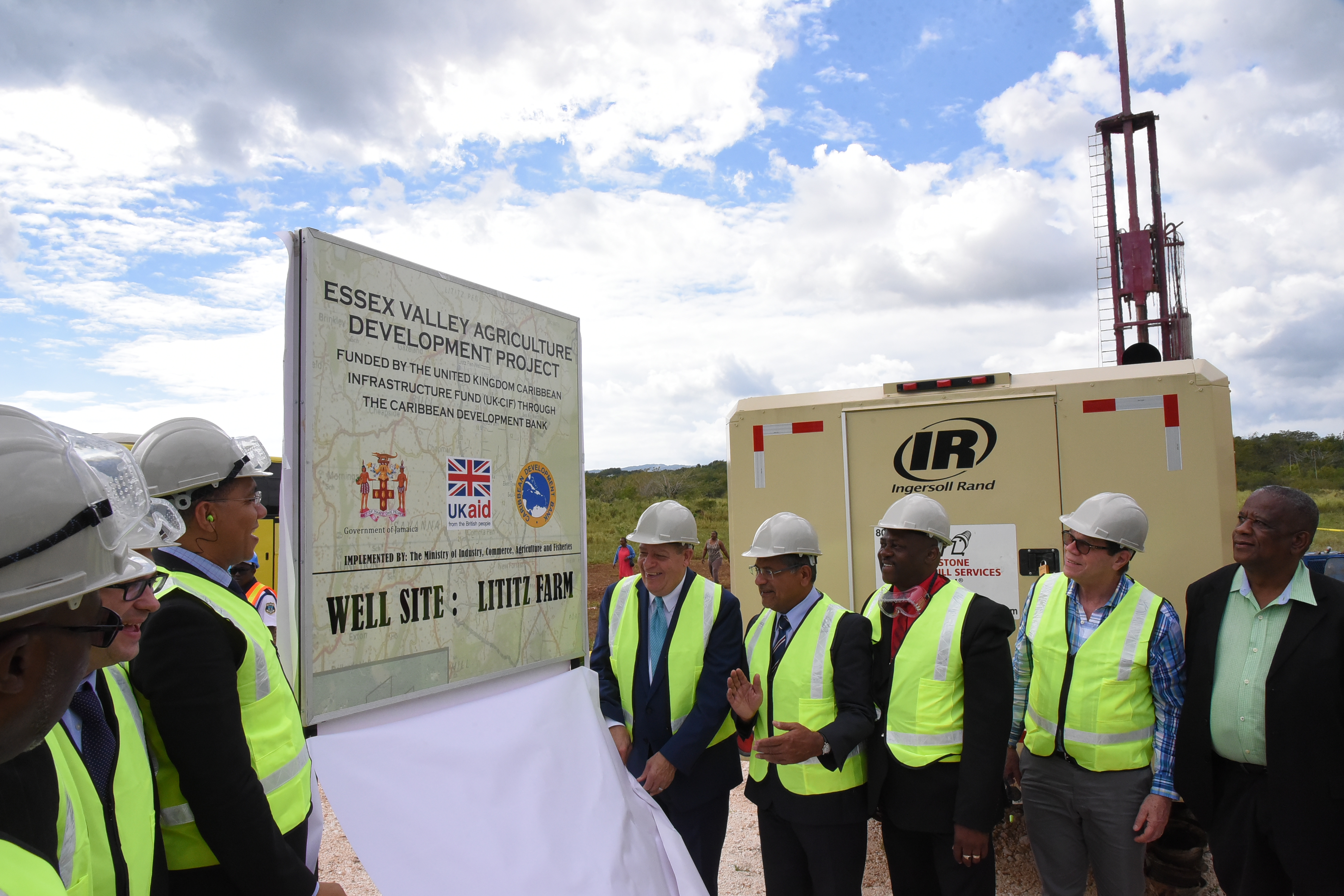 Government officials and stakeholders wear protective gear on a drill site for a project in Jamaica