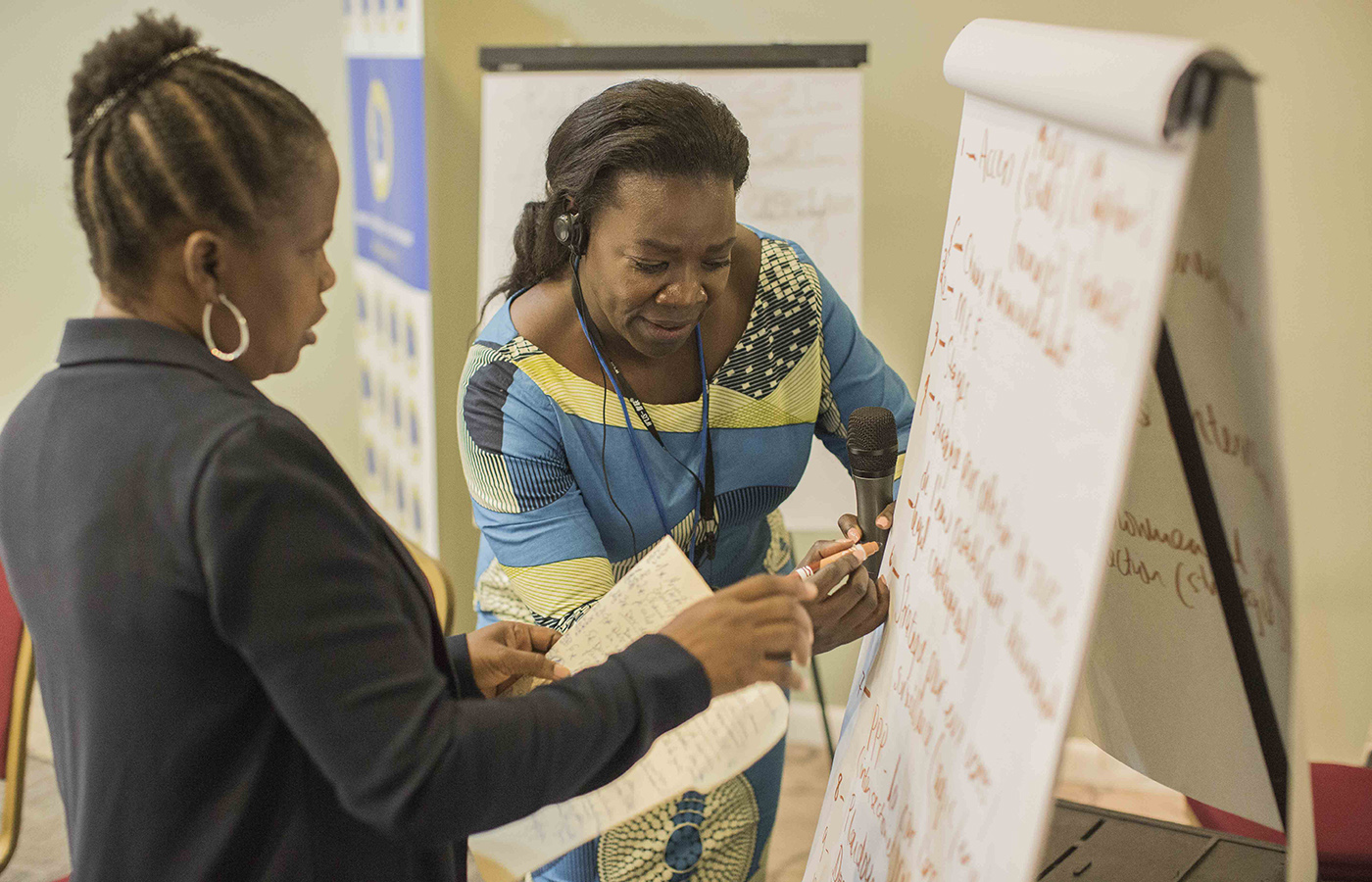 Two women writing on flipchart.