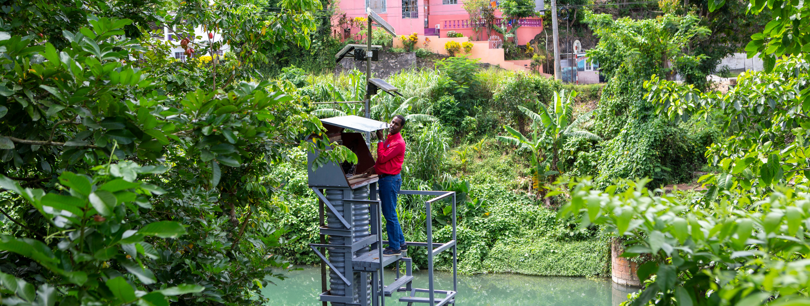 Man in red shirt checking flood monitoring station in Jamaica