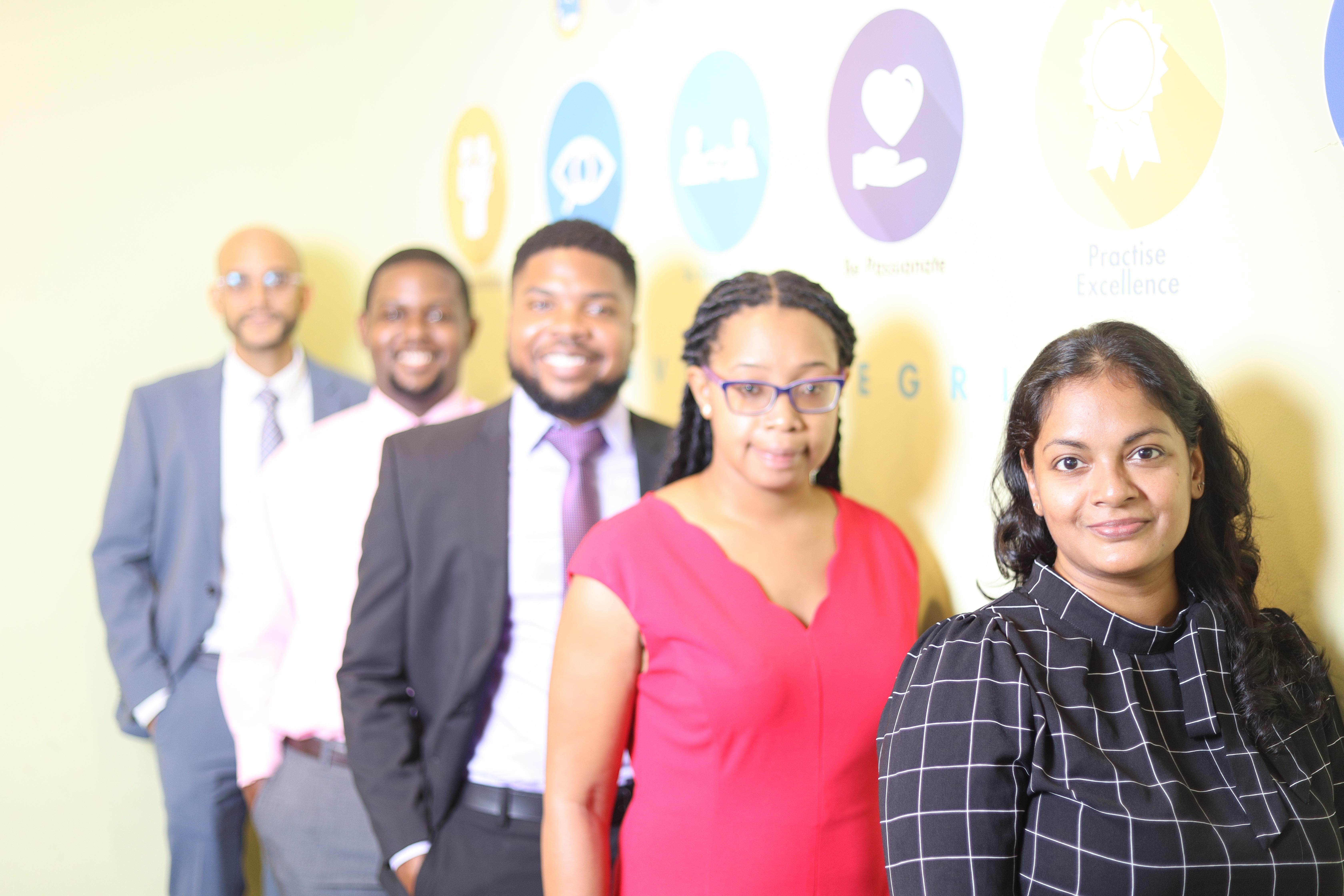 young professionals posing against CDB's core values wall