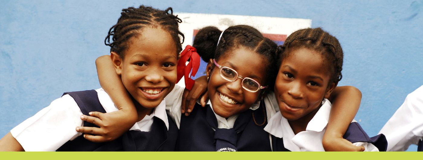 portrait of three African schoolgirls smiling with arm around each other