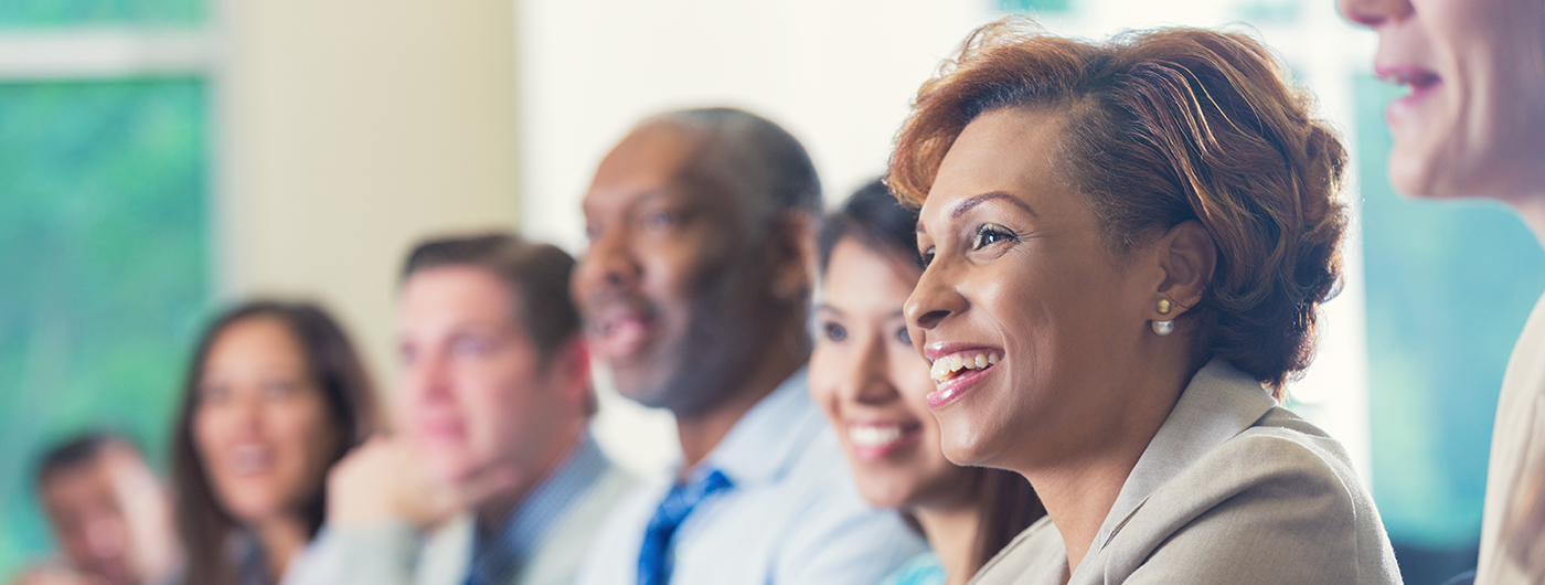 African American businesswoman and others listening to seminar speaker at business conference