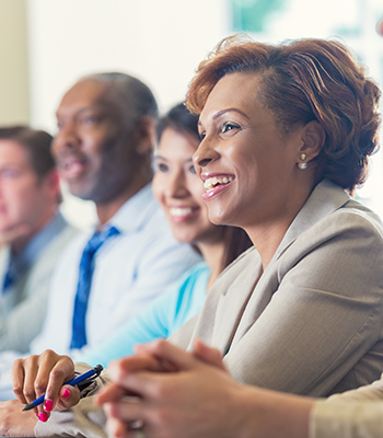 African American businesswoman and others listening to seminar speaker at business conference