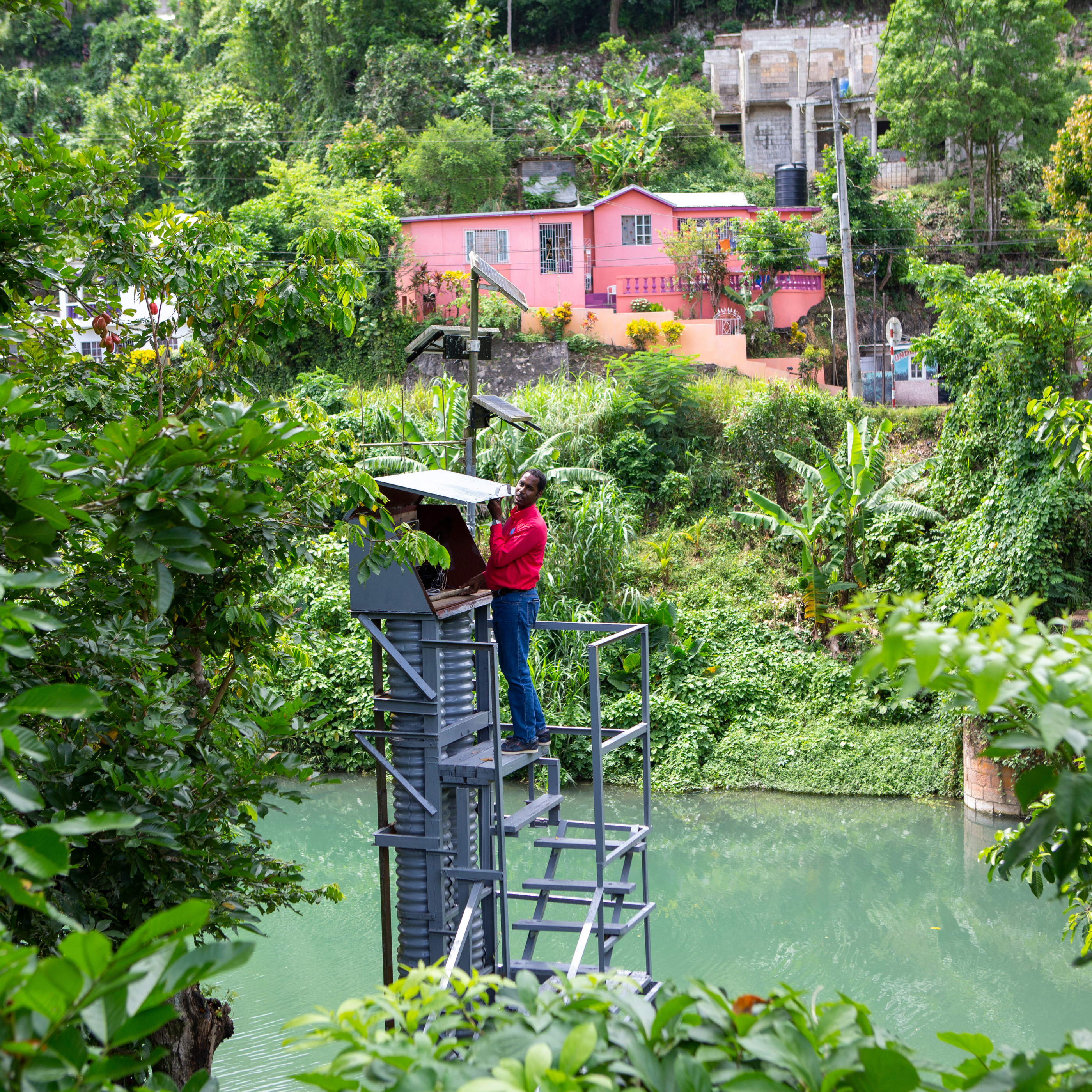 man in red shirt checking flood monitoring station in Jamaica