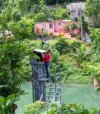 man in red shirt checking flood monitoring station in Jamaica