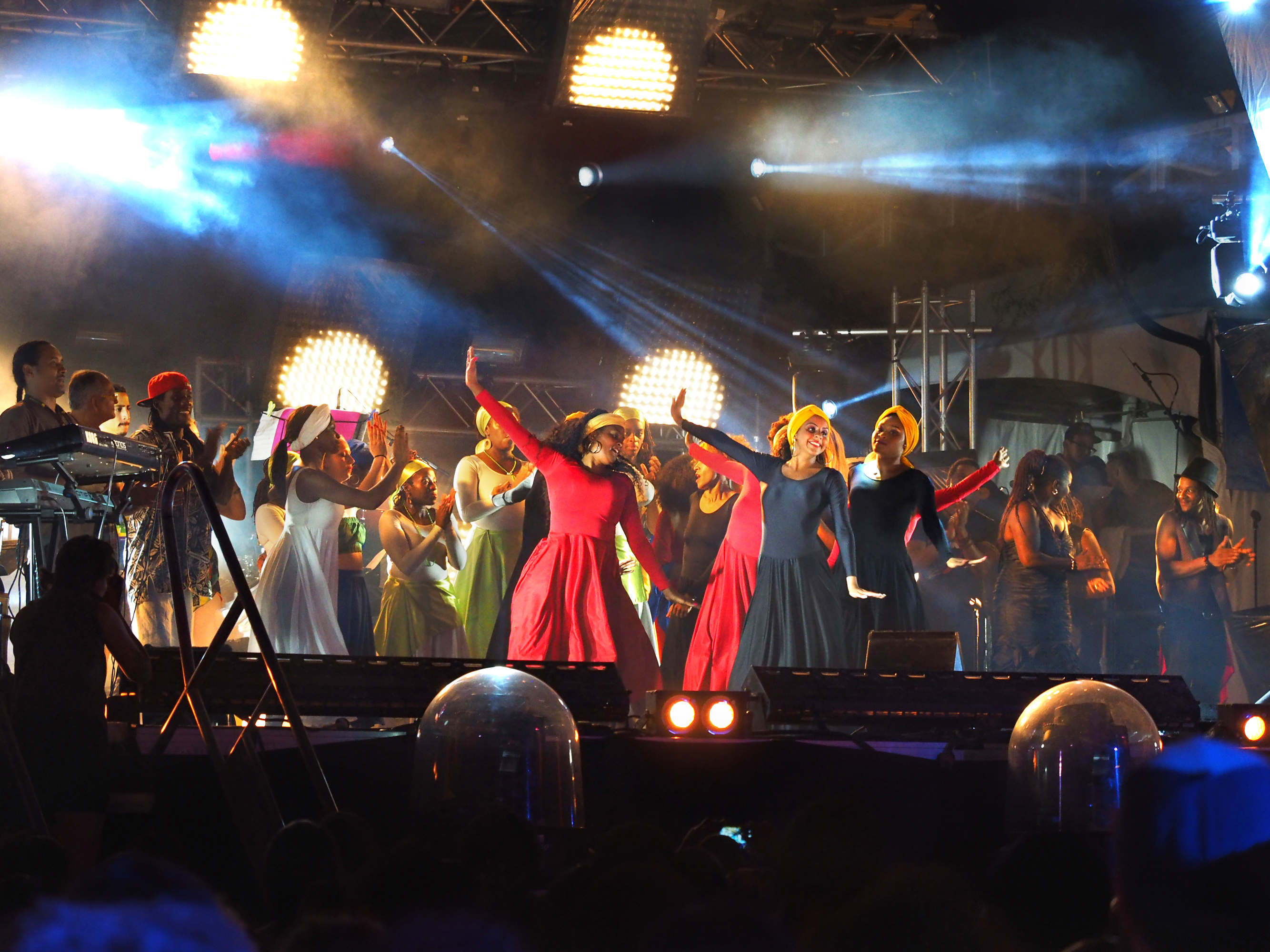 Dancers on a crowded stage smile at audience