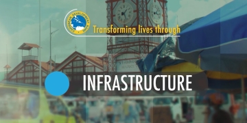 screen capture of video slide with city of Georgetown, Guayana as backdrop with the word infrastructure highlighted