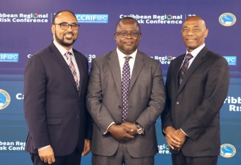 CDB President and CCRIF SPC CEO in dark suits with step and repeat backdrop behind him featuring conference logo