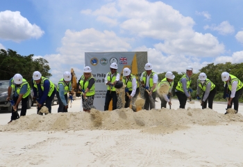 row of persons in reflector vests with shovels in hand, breaking ground