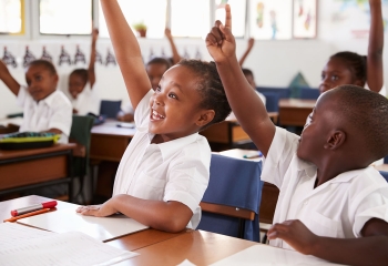 Kids raising hands during elementary school lesson, close up