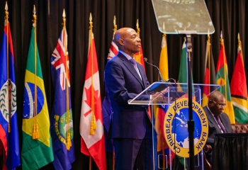 CDB President standing at lectern with member flags in the background
