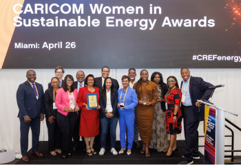 Several people stand on a stage below the words CARICOM Women in Sustainable Energy Awards 