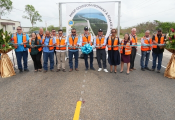 Group of persons behind long ribbon opening new road in Belize 