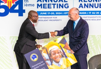 Isaac Solomon on the left hands PB Scott on the right a card with the words partnering for a better future as the two men shake hands