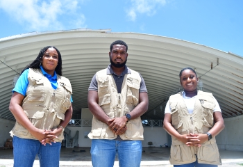 two females and one male dressed casually wearing utlitity jackets stand in front of a bunker-like structure