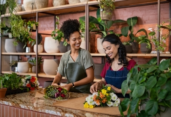 Two happy and smiling young woman florist working together in flower shop. 