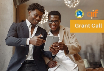 two black male entrepreneurs standing looking at a tablet smiling in business attire 
