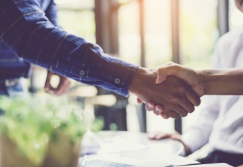Businessmen hold hands and greet 