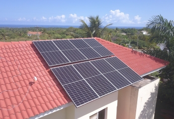 Monocrystalline solar panels 445W installed on roof of building in Caribbean with sea visible in background