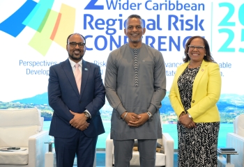 Two males and one woman standing on stage smiling in business attire