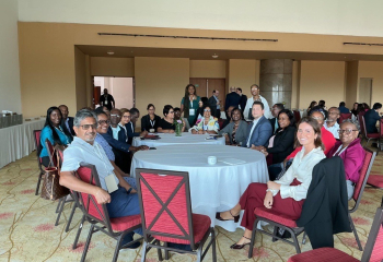 group of procurement professionals seated around two large round tables looking ahead and smiling