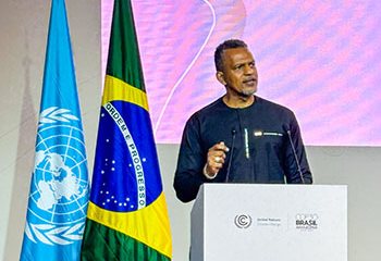 CDB President Daniel Best stands at a podium during COP30 event, positioned next to the United Nations flag and the Brazilian flag