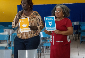Two participants in a Basic Needs Trust Fund workshop hold tiles representing their priority Sustainable Development Goals