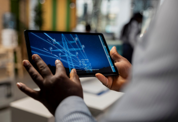 Close up of engineer working for green tech company designing eco power line towers on tablet. RD specialist uses CAD app on device to optimize transmission tower systems, reducing carbon footprint