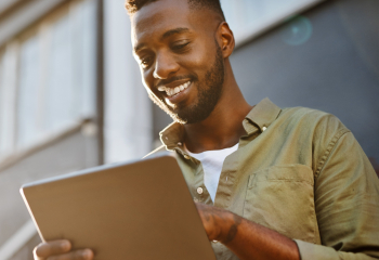 Caribbean man smiling and looking at his tablet. 