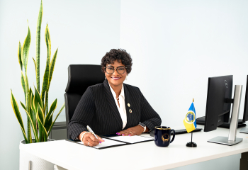 ady sitting at a desk holding a pen in black and white business atire smiling 