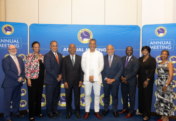 a row of persons standing in formal attire ahead of a bright blue and yellow backdrop