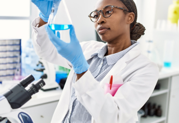 Woman looks at solution in bottle in lab