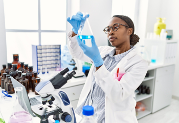 Woman looks at solution in a bottle in lab