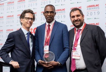 CDB's Joseph Williams and two others standing against backdrop at prize ceremony.