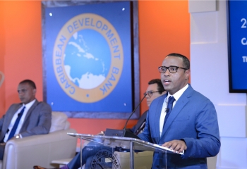 Dr. Ram in a blue suit standing at the lectern delivering his remarks at the Annual News Conference