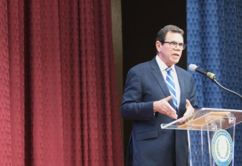 Dr Warren Smith in navy suit at lectern