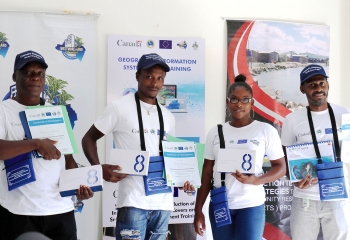 three males and one female pose with certificates and tablets with branded banners in the background