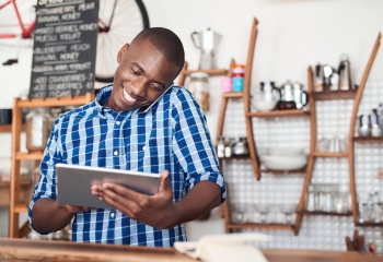 black male entrepreneur using a tablet device in a blue and white plaid shirt
