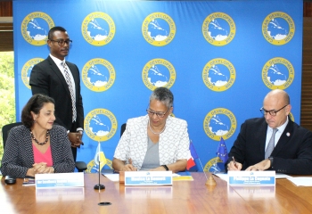 Vice-President (Operations) of the Caribbean Development Bank, Monica La Bennett (center) and Philippe La Cognata, Atlantic Regional Director, Agence Française De Développement (right) sign the finance agreement. At left, Ambassador Daniela Tramacere, Head of the European Union Delegation to Barbados, the Eastern Caribbean, OECS and CARICOM/CARIFORUM and CDB Senior Legal Counsel Dave Waithe (second from left) look on.