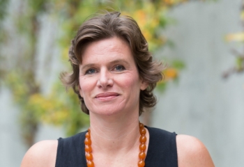 Professor Mariana Mazzucato wearing a black shirt and orange necklace