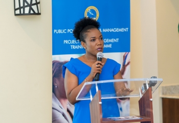 Barbados Minister of Economic Affairs Marsha Caddle standing at lectern in blue dress.