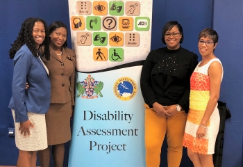 Four women standing on either side of a colourful pull up banner