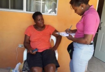 standing lady in pink shirt interviewing seated woman