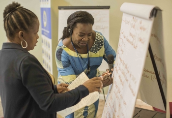 Two women writing on flipchart.