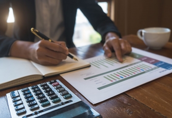 man in suit with calculator and spreadsheets