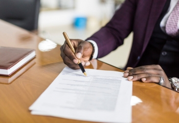 image of hands of man in purple suit signing an agreement