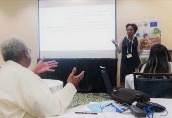 standing workshop presenter at the front of the room speaking with a seated participant