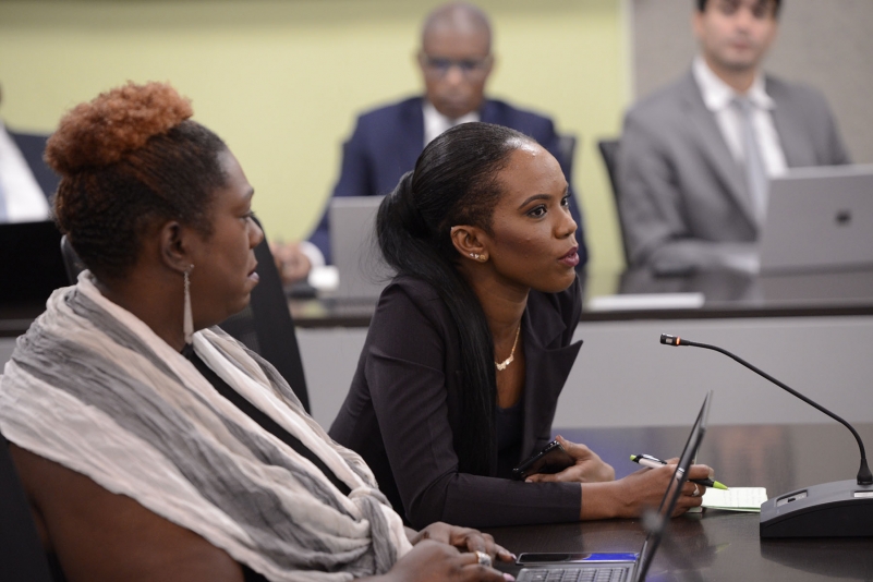 Young female journalist, seated at table in a black suit asks question