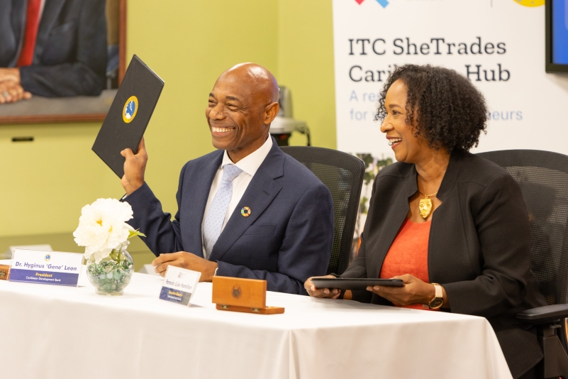 male and female seated at a desk signing documents